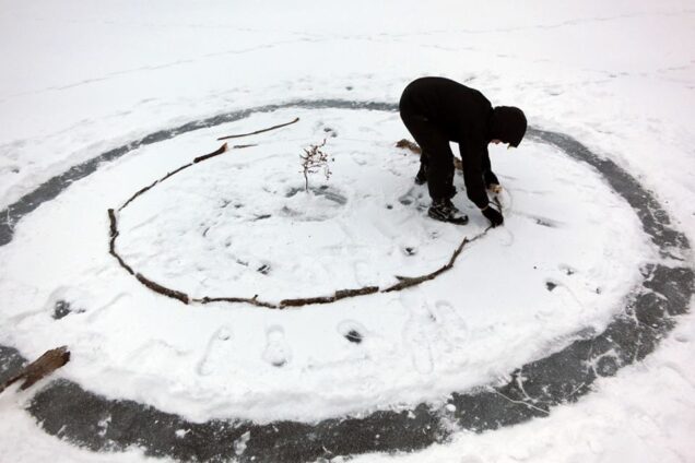 Person arranging sticks in snow