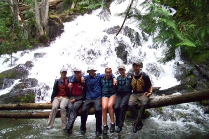 Students sitting on tree in front of waterfall in summer